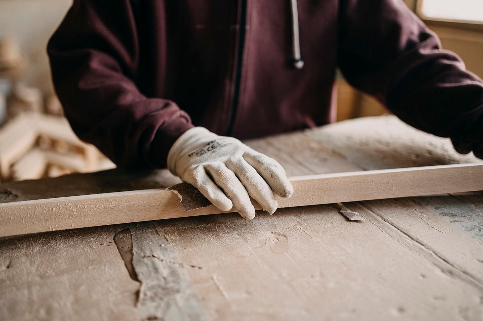 Mains travaillant une pièce de bois dans un atelier.